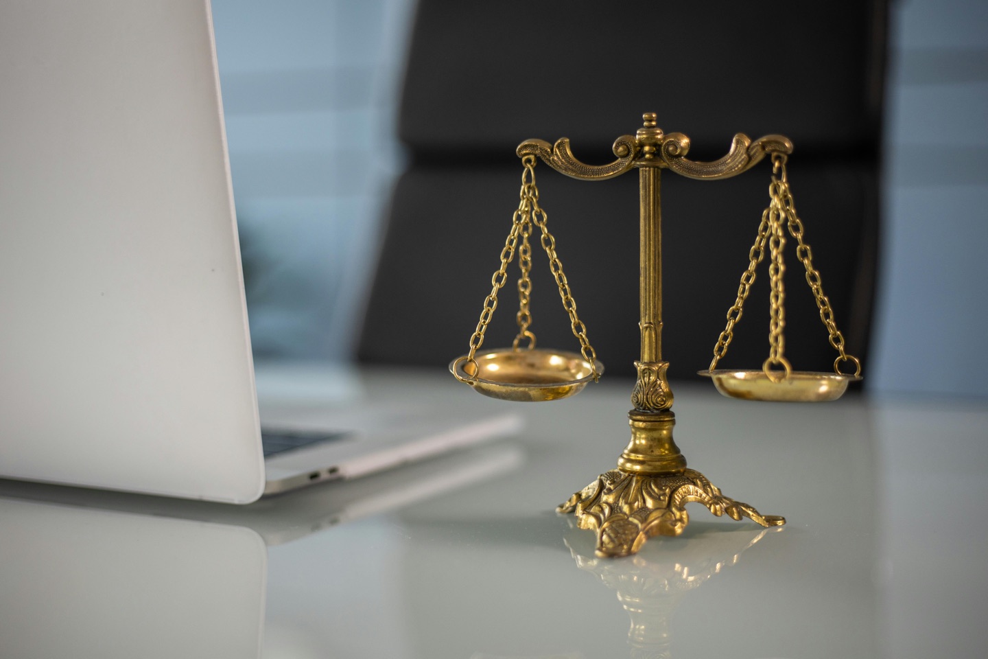 Balance scales beside a laptop, illustrating judgement and accountability